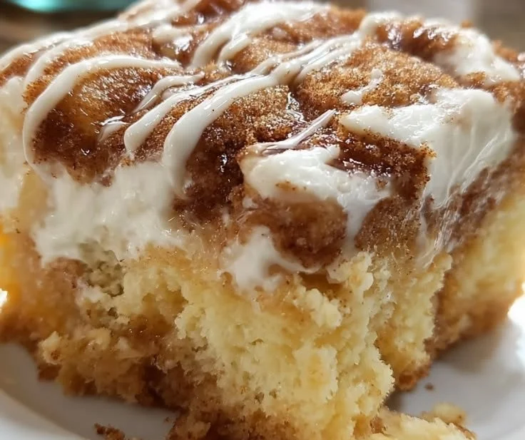 Delicious cinnamon roll poke cake topped with creamy frosting and cinnamon swirls