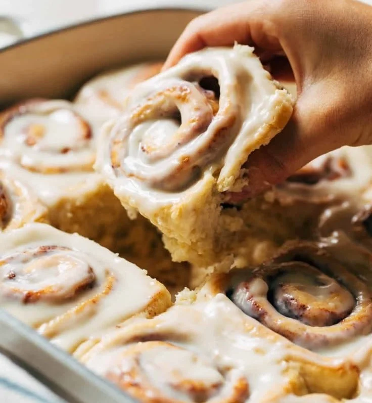 Delicious homemade cinnamon rolls topped with frosting and cinnamon sugar