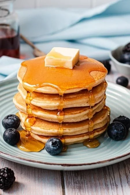 Delicious fluffy American pancakes stacked with syrup and berries