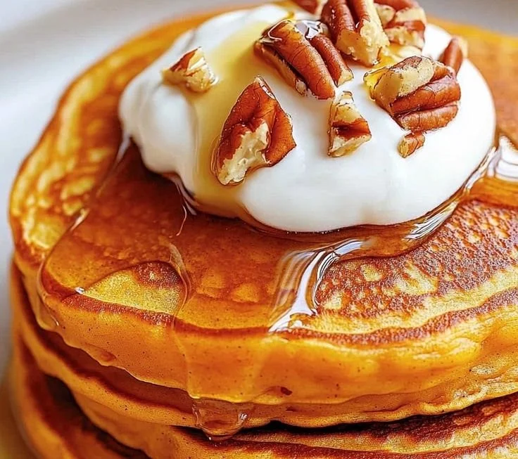 Stack of fluffy sweet potato pancakes topped with syrup and berries