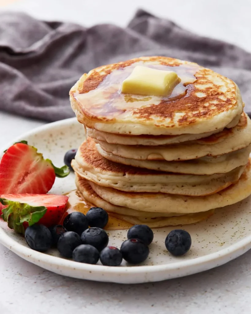 Image of fluffy gluten-free pancakes topped with fresh berries and syrup