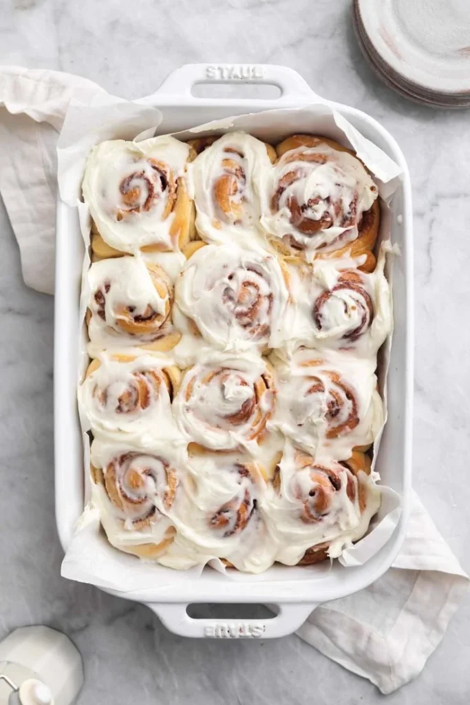 Freshly baked homemade cinnamon rolls drizzled with icing on a plate
