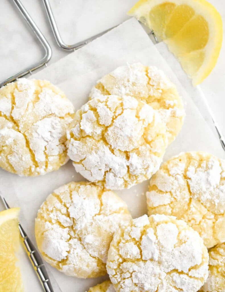 Delicious Lemon Crinkle Cookies dusted with powdered sugar on a white plate.