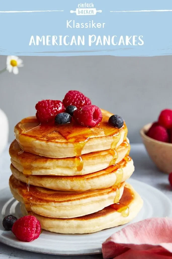 stack of fluffy pancakes topped with syrup and berries
