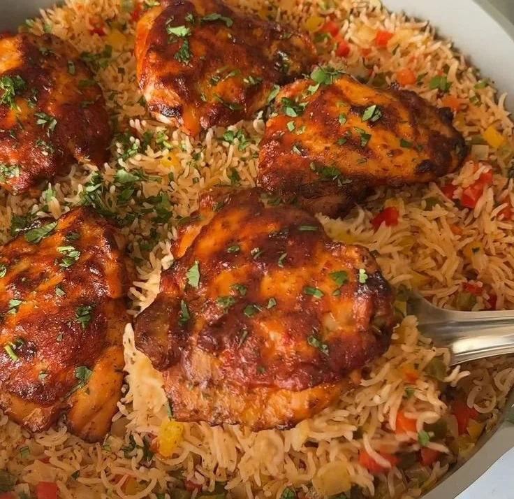 Plate of peri peri chicken served with rice and garnished with fresh herbs.