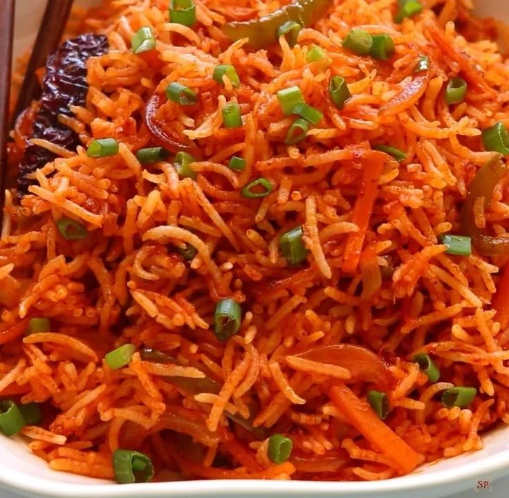 Plate of spicy Schezwan Fried Rice with vegetables and herbs