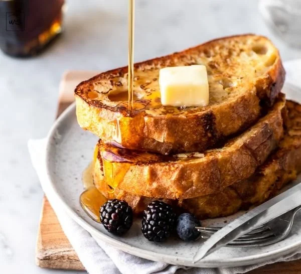 Delicious slice of sourdough French toast topped with fresh berries and syrup