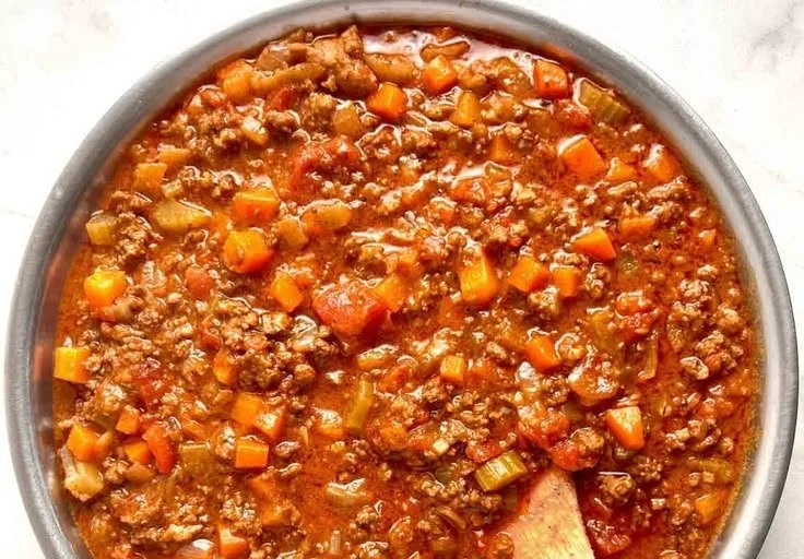 A bowl of authentic Bolognese sauce with fresh ingredients and herbs.