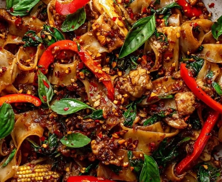 Plate of authentic Thai drunken noodles (Pad Kee Mao) with vegetables and herbs