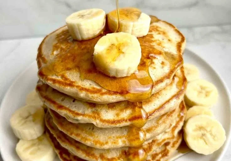 Fluffy banana pancakes stacked with fresh bananas and syrup
