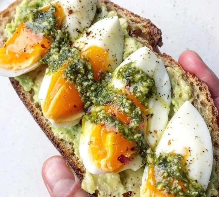 Breakfast toast topped with avocado and pesto for a healthy meal