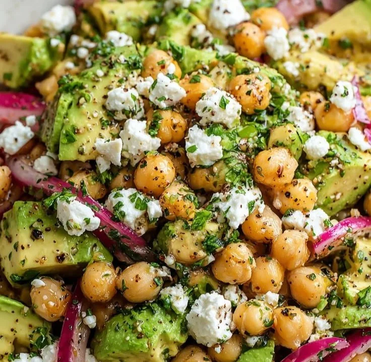 Chickpea avocado salad with feta served in a bowl, garnished with fresh herbs