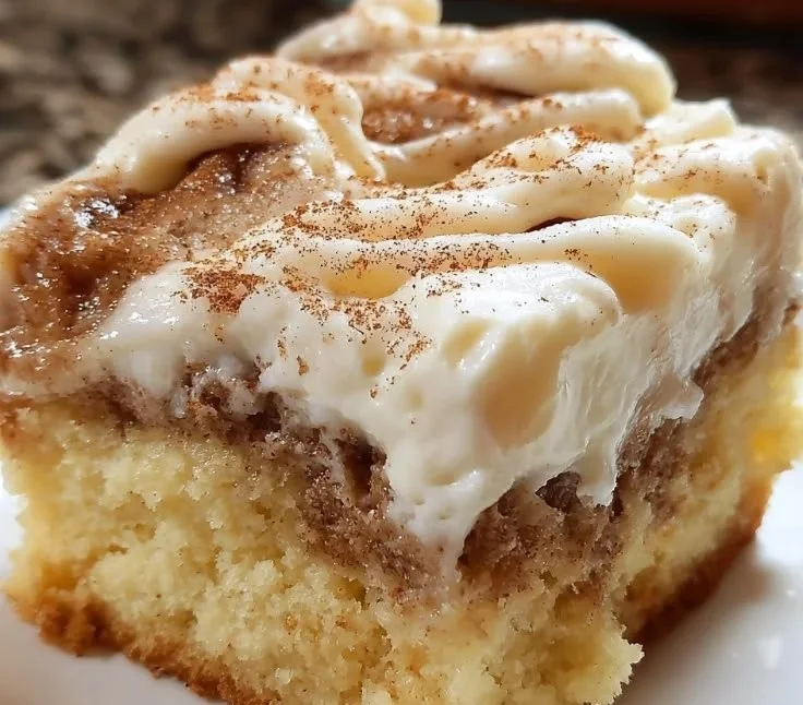 Delicious Cinnamon Roll Poke Cake topped with creamy icing and cinnamon swirls.
