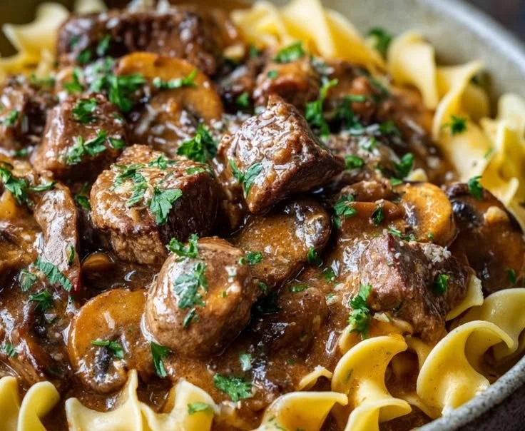 Classic beef stroganoff served with noodles and garnished with parsley