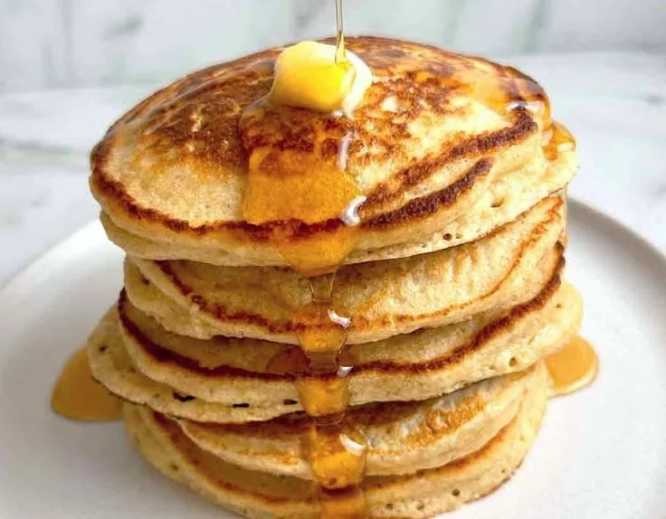 Healthy oatmeal pancakes stacked on a plate with fresh fruit