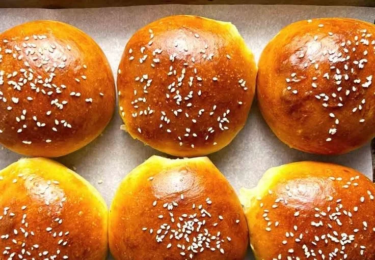 Freshly baked homemade hamburger buns on a wooden table