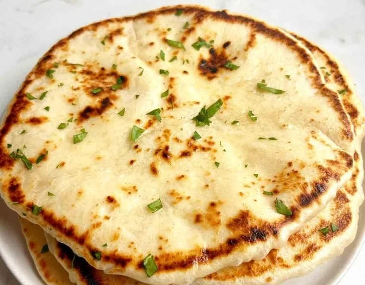 Homemade sourdough naan served with various dips and dishes.
