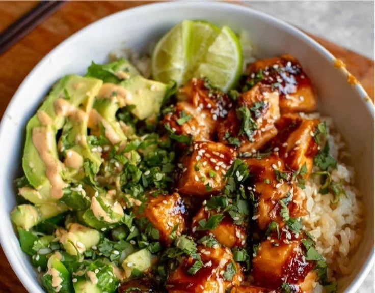 Honey glazed salmon rice bowl topped with fresh vegetables and sesame seeds