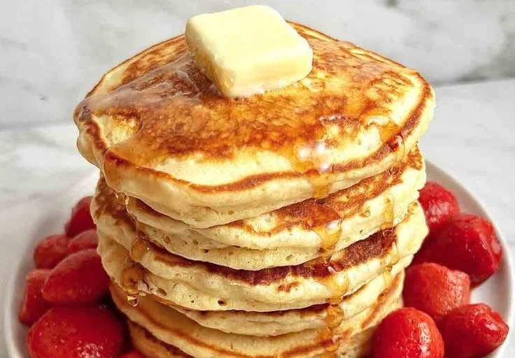 Stack of fluffy pancakes topped with syrup and berries