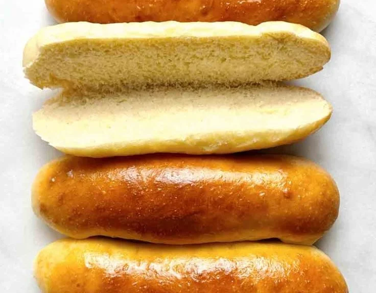 Homemade hot dog buns cooling on a rack ready for grilling.