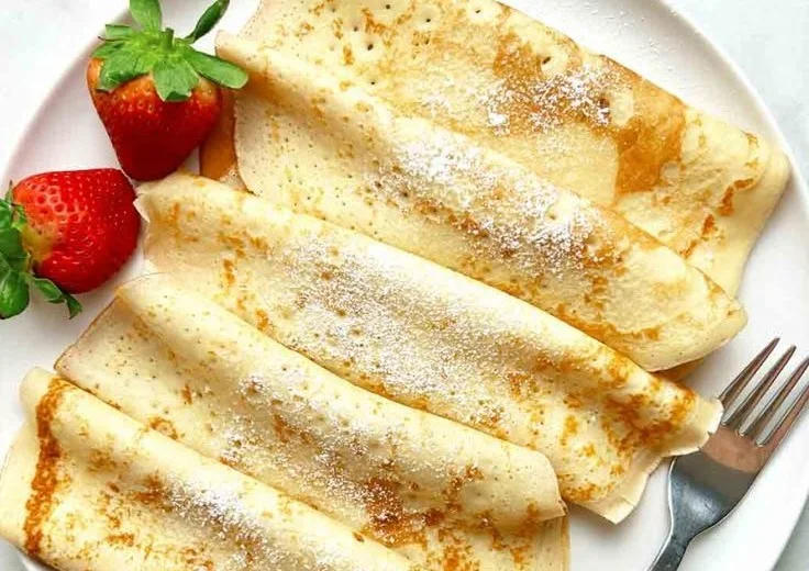 Delicious traditional Swedish pancakes stacked on a plate with berries.