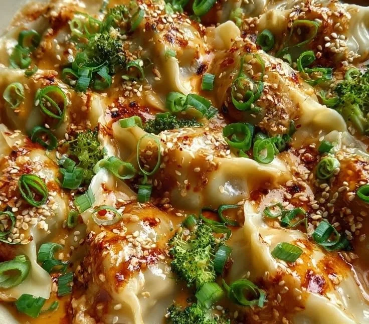 Oven-baked dumplings drizzled with creamy peanut sauce on a plate