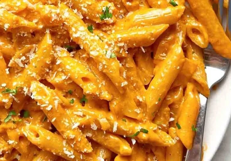 A plate of creamy Penne alla Vodka garnished with fresh basil.