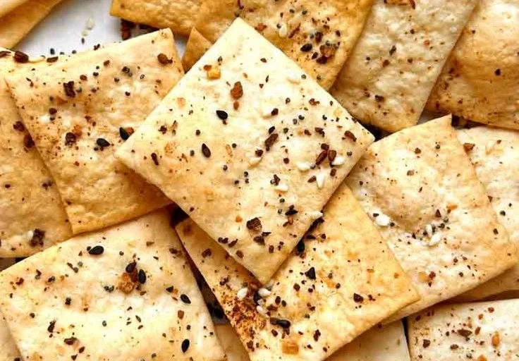 Crispy homemade sourdough crackers stacked on a plate