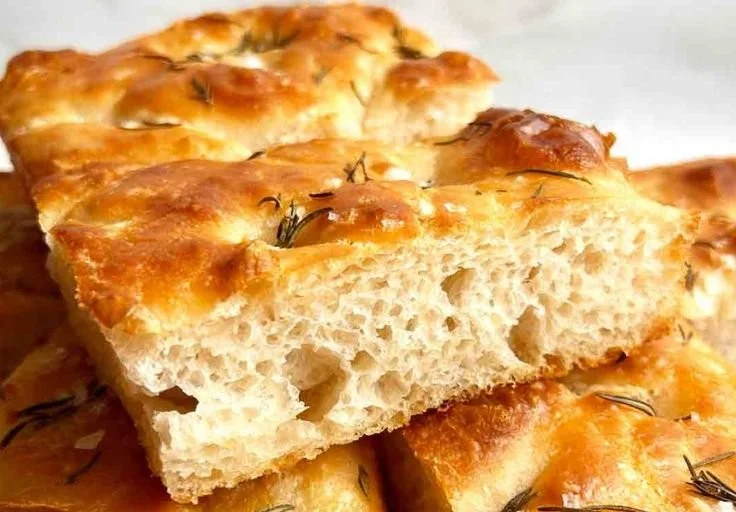 Freshly baked sourdough focaccia bread with herbs and olive oil.
