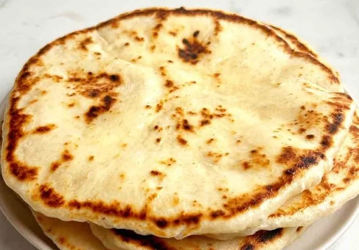 Freshly baked sourdough naan bread on a wooden surface
