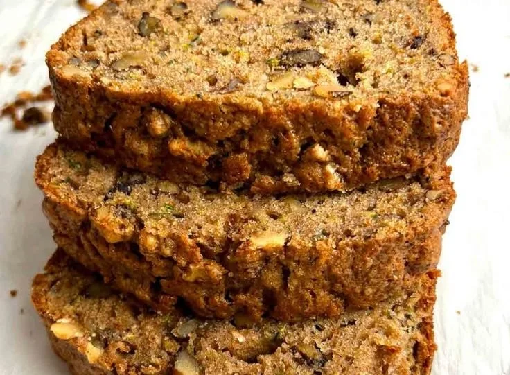 Loaf of homemade sourdough zucchini bread with slices on a wooden board.