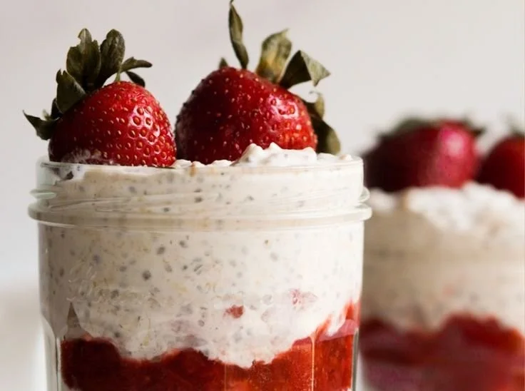 Bowl of strawberry cheesecake overnight oats topped with fresh strawberries and crumbs