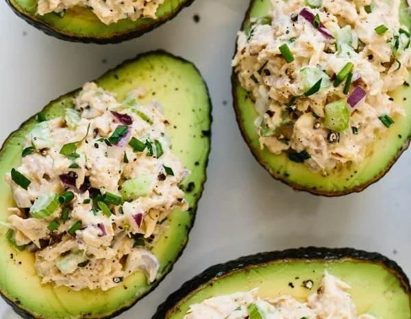 Tuna stuffed avocados filled with fresh ingredients and served on a plate.