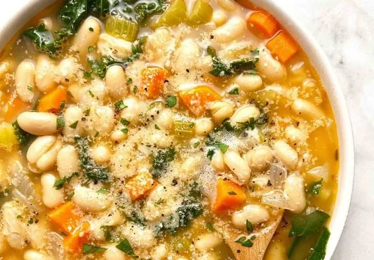 Bowl of homemade white bean soup garnished with herbs and spices.