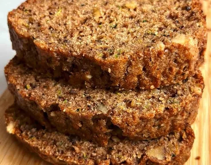 Homemade zucchini bread fresh out of the oven, garnished with nuts.