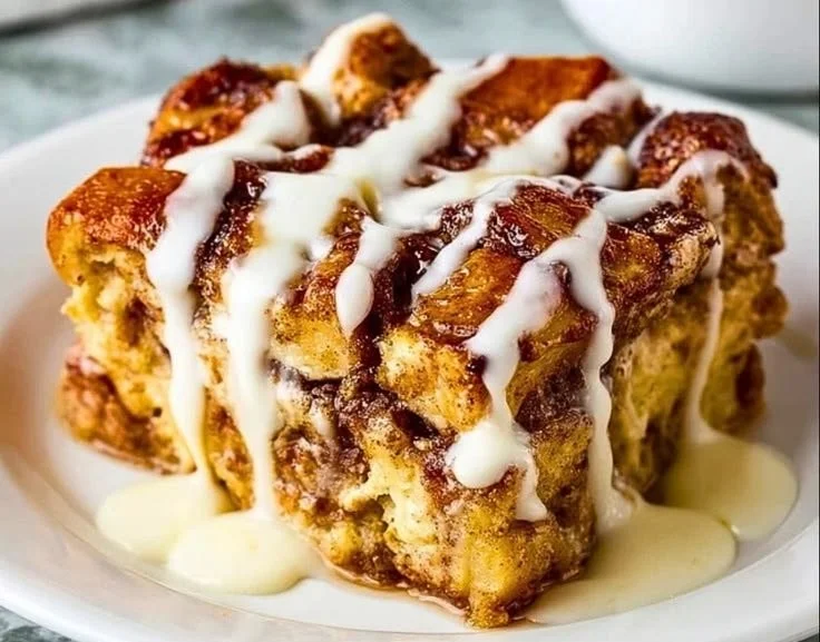 Delicious Cinnamon Roll French Toast Bake topped with icing and berries