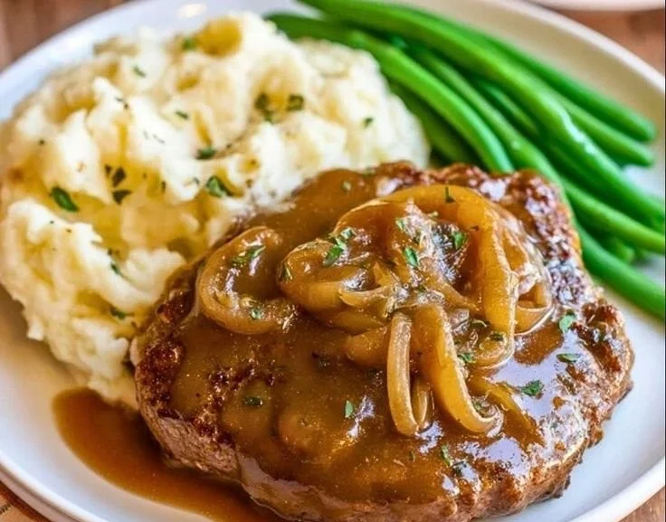 Crock Pot cube steak simmering in gravy, ready to serve with mashed potatoes.
