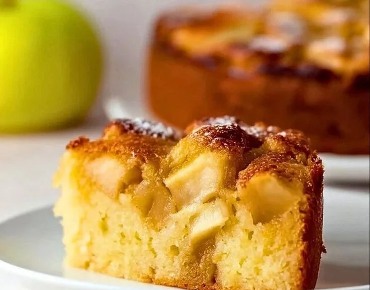 Delicious slice of Italian Apple Cake on a white plate with a fork