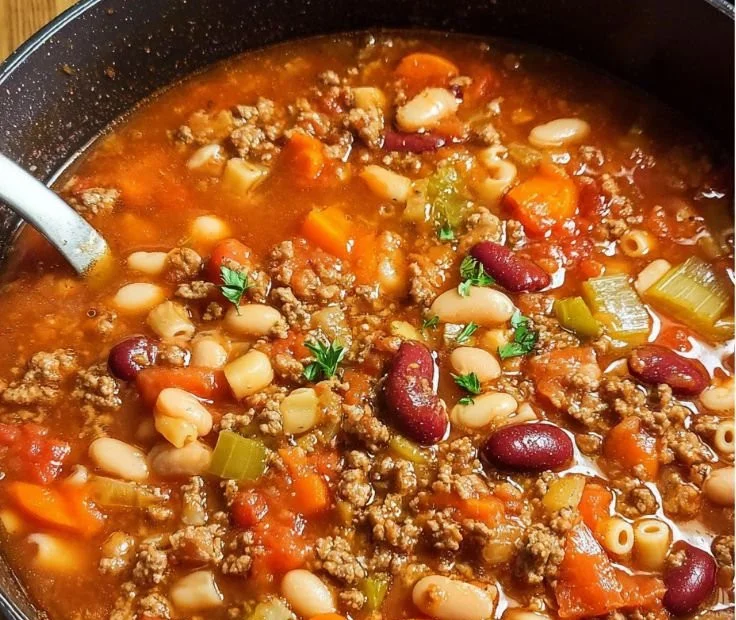 Bowl of Pasta e Fagioli soup with beans and pasta garnished with herbs.