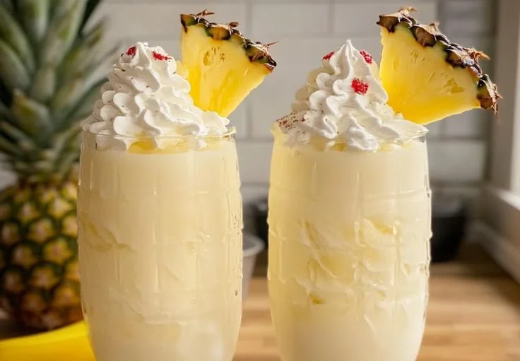 Delicious Piña Colada milkshake topped with whipped cream and a cherry.