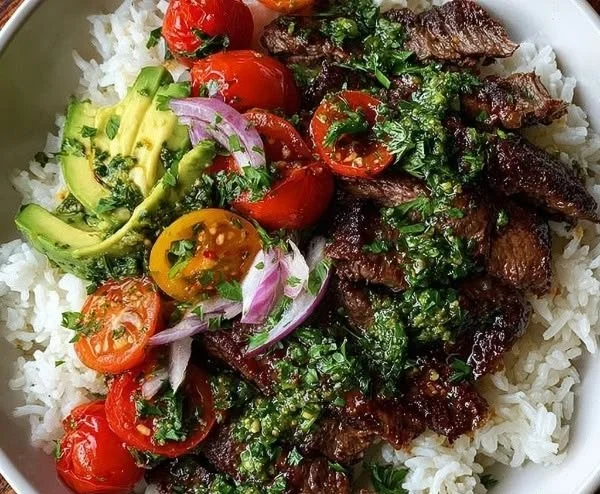 Rice bowl topped with juicy skirt steak and garnished with fresh vegetables