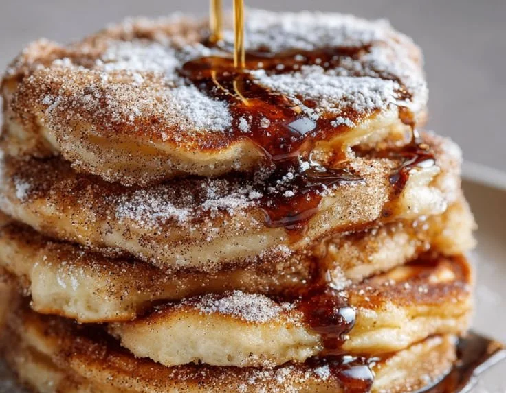 Delicious Spanish churro pancakes topped with cinnamon sugar and drizzled with chocolate.