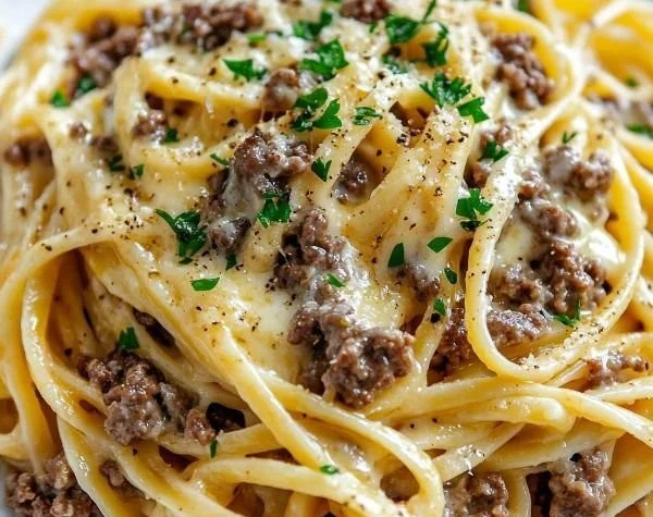 Cheesy garlic butter linguine topped with ground beef and herbs in a bowl