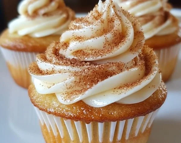 Freshly baked cinnamon roll cupcakes with icing on top.