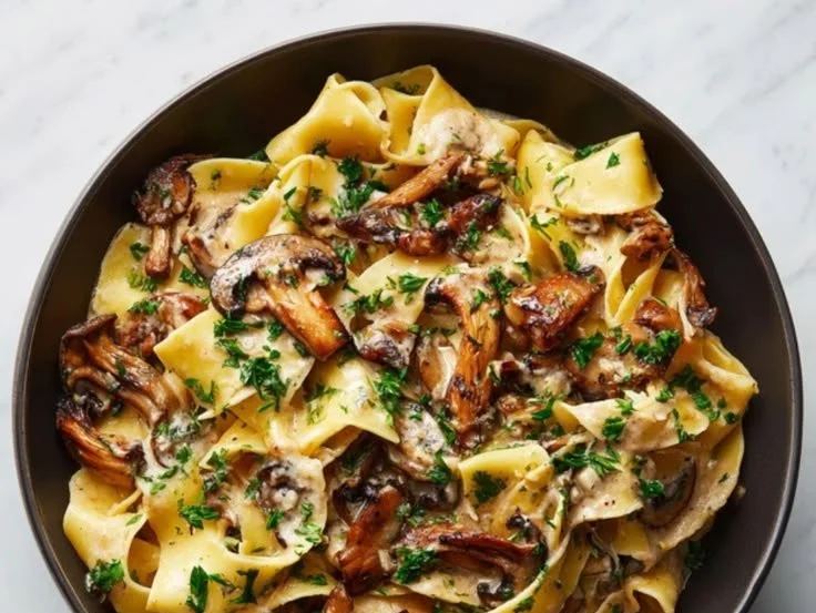 Creamy mushroom pappardelle dish with fresh herbs and parmesan on top