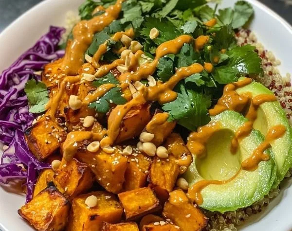 Thai Peanut Buddha Bowl with Sweet Potatoes topped with fresh vegetables and peanut sauce