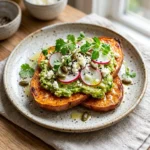 Healthy sweet potato toast topped with avocado and seeds on a wooden board